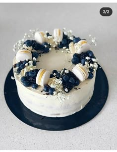 a white cake topped with blueberries and seashells on top of a black plate