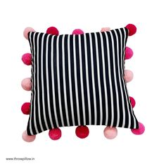 a black and white striped pillow with pink pom - poms on the bottom