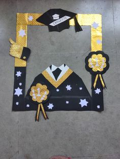 a graduation decoration made out of paper and gold foil on the floor, with stars around it