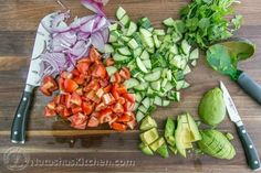 chopped up vegetables are sitting on a cutting board with a knife next to them, along with an avocado