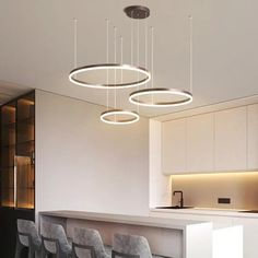 the lights are hanging from the ceiling above the kitchen counter and bar stools in front of an island