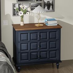 a blue dresser with flowers and pictures on the wall