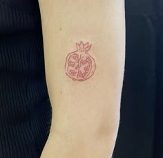 a woman's arm with a tattoo on it that has a pomegranate in the shape of a heart