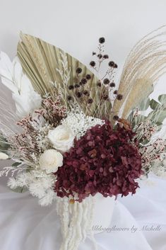 a vase filled with flowers and greenery on top of a white cloth