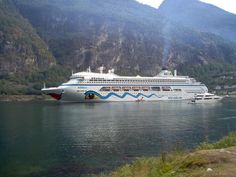 a large cruise ship in the water near mountains