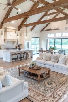 Spacious modern living room with white sofas, a wooden coffee table, and a kitchen in the background under a high ceiling with wooden beams. Classy Farmhouse Decor, Boho Farmhouse Living Room, Modern Farmhouse Living, Dream Life House, Casas The Sims 4, Modern Farmhouse Living Room, Dream House Rooms, Farmhouse Interior