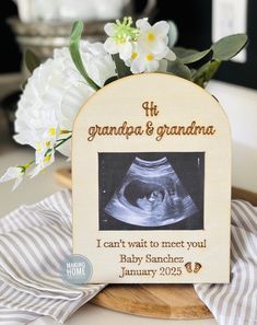 a wooden plaque with a picture of a baby's diaper on it and flowers in the background