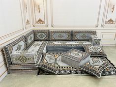 an elaborately decorated couch in a room with white walls and gold trimmings