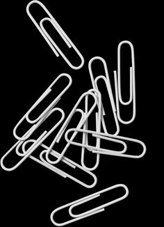 several white paper clips on a black background