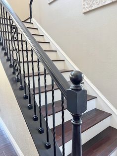 a stair case with black railing and wood handrail