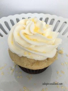 a cupcake with white frosting and yellow sprinkles on a plate