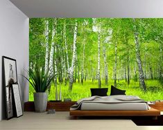 the bedroom is decorated with green trees and white walls, along with a large bed