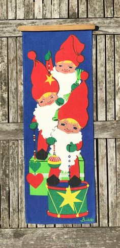 a towel hanging on the side of a wooden fence with santa claus and other christmas decorations