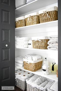 the shelves in this bathroom are filled with white towels and wicker baskets, along with toiletries