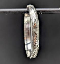 A pretty classic hinged sterling silver bangle bracelet with a leafy engraved design on one side. Inside the bangle has a patent number, a makers mark for Bracelon Ltd and full English silver hallmarks with a date letter for 1981. In good vintage condition. Inner circumference: 17.5 cm Width: 9 mm Weight: 12 grams approx Materials: Sterling silver Postage Our standard UK postage option uses Royal Mail second class post, if you require your order faster then you can upgrade postage options for an Classic Etched Bangle Bracelets, Classic Etched Bangle Bracelet, Heirloom Bangle Bracelet With Polished Finish, Classic Etched Bangle For Wedding, Elegant Silver Jewelry With Engraving Option, Elegant Etched Bangle For Formal Occasions, Classic Etched Wedding Bangle, Classic Etched Bangle Jewelry, Classic Engraved Sterling Silver Bracelet