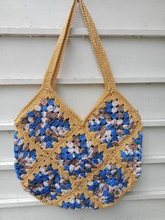 a crocheted bag hanging on the side of a building with blue and white flowers