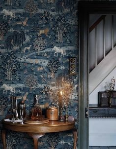 a table with candles on it in front of a wallpapered stairway and stair case