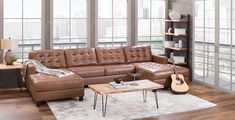 a living room with a brown leather couch and guitar on the coffee table in front of it