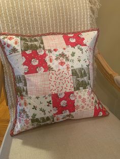 a white chair with a red and green patchwork pillow on it