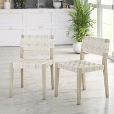 two wooden chairs sitting next to each other in a room with white cabinets and windows