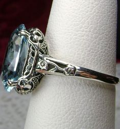 Simulated Aquamarine Ring Edward Design#70 Custom Made Here we have an Edwardian reproduction ring in sterling silver filigree with a perfect Simulated/Man-made blue aquamarine gemstone solitaire. This full cut oval gem is 14mm in length and 10mm in width (slightly smaller gemstone also available upon request). This ring also sits 7mm off the finger. The inside of the band is marked 925 for solid sterling. Notice the beautiful leaf design of the silver filigree setting and etched band. This is a Sky Blue Topaz Ring, Silver Gold Jewelry, Filigree Jewelry, Aquamarine Ring, Sterling Silver Filigree, Blue Gems, Aquamarine Rings, Silver Art, Sterling Silver Flowers