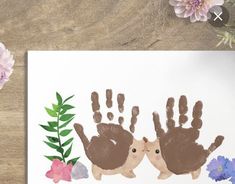 two handprints with flowers and leaves are on a table next to a card