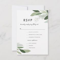 a wedding rsvp card with greenery on the front and bottom, in white