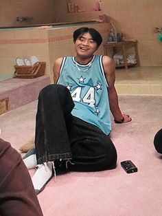 a young man sitting on the floor with his feet up in front of him and smiling