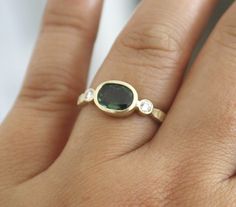 a woman's hand with a ring on it and a green stone in the middle