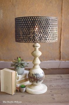 a lamp sitting on top of a wooden table next to a book and potted plant