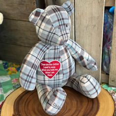 a teddy bear sitting on top of a tree stump with a heart patch in the middle