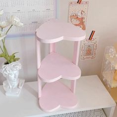 a pink shelf sitting on top of a desk next to a vase with white flowers