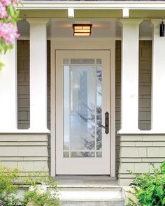 a white front door on a house with flowers in the foreground and bushes behind it