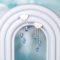 Indulge in the charming whimsy and elegance of these Cloud and Rain Drop Dangle Earrings. The delicate chains with blue teardrop crystals elegantly dangle like rain drops, while the satin finish on the cloud adds a unique texture that will surely catch the eye. Crafted with solid 925 sterling silver, these earrings are not only gorgeous but also of high quality. Perfect for those who love to match their accessories to the ever-changing weather! Sold as a pairMaterials: 925 sterling silver, resin Sterling Silver Drop Jewelry With Dangling Charms, Silver Drop Chandelier Earrings, Silver Drop Jewelry With Dangling Charms, Sterling Silver Teardrop Dangle Earrings With Pearl Drop, Light Blue Dangle Earrings In Sterling Silver, Light Blue Sterling Silver Dangle Earrings, Light Blue Sterling Silver Teardrop Earrings, Teardrop Chandelier Earrings With Dangling Charms As Gift, Blue Teardrop Sterling Silver Chandelier Earrings