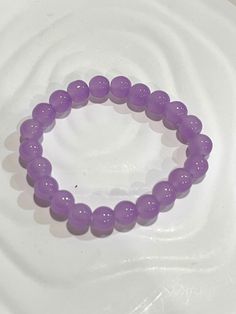 a purple beaded bracelet sitting on top of a white plate