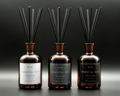 three bottles with reeds in them sitting on a gray surface next to each other