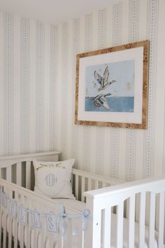 a baby's room with a white crib and striped wallpaper