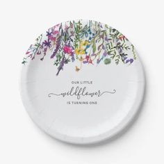 a white paper plate with colorful flowers and the words madeline's first birthday printed on it