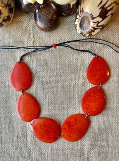 Handmade in Ecuador Necklace Length: Adjustable Length 14 -31 Inches Due to this item being handmade and the nature of the Tagua Nut the size and the color may vary from piece to piece Fair Trade Red Jewelry For Festivals, Red Fair Trade Jewelry For Festivals, Fair Trade Orange Jewelry Gift, Orange Fair Trade Jewelry Gift, Vintage Brown Jewelry For The Beach, Red Fair Trade Jewelry As A Gift, Adjustable Red Nature-inspired Jewelry, Adjustable Fair Trade Jewelry For Gifts, Adjustable Orange Artisan Necklace