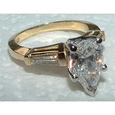 an engagement ring with a pear shaped diamond in the center and baguetts on each side