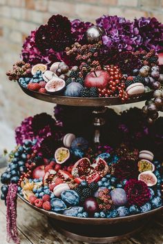 two tiered trays filled with fruits and vegetables on top of a wooden table