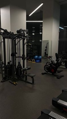 a gym with machines and exercise equipment in the middle of an empty room at night