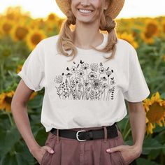 "Wildflowers" - the perfect T-shirt for any occasion! Whether you're a man or a woman, this unisex tee is sure to bring a smile to your face. With its vibrant colors and floral designs, it's sure to bring out the wild side in you.From the garden to the meadow, this T-shirt is sure to bring out the beauty of nature. With its trendy design, you'll be sure to stand out in the crowd. From roses to marigolds, dandelions to tulips, and even the occasional bonnet, this T-shirt is sure to bring out the Cotton Short Sleeve T-shirt With Sunflower Print, Casual Floral Print Crew Neck T-shirt, Casual Cotton T-shirt With Plant Print, White T-shirt With Sunflower Print For Spring, Summer Crew Neck T-shirt With Plant Print, Spring Casual Tops With Custom Print, Casual Spring Tops With Custom Print, Casual Custom Print Top For Spring, Spring Plants Print Short Sleeve T-shirt