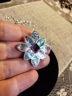 "Super HIGH QUALITY Everything! All Sterling Silver in a flower shape; Petals are all made of inlaid ABALONE (specifically from New Zealand and called Paua Shell - very intense colors); Center is a 7x7mm Sugarloaf cut AMETHYST. **THIS PIECE IS BOTH A PENDANT AND A PIN OR BROOCH** Measures 1.25\" each direction. I am including an 18\" Sterling Silver chain too. Hallmarked SAJEN 925 By the renowned designers RICHARD & MARIANNA JACOBS, the OFFERINGS line by SAJEN. Made in Bali. Contact me with Sterling Silver Jewelry With Purple Flower Charm, Purple Sterling Silver Flower-shaped Jewelry, Purple Sterling Silver Jewelry With Flower Charm, Purple Flower-shaped Sterling Silver Jewelry, Purple Flower-shaped Nickel-free Jewelry, Amethyst Flower-shaped Jewelry Gift, Flower Shaped Amethyst Jewelry For Gift, Purple Flower Shaped Gemstone Jewelry, Amethyst Flower Pendant Jewelry Gift