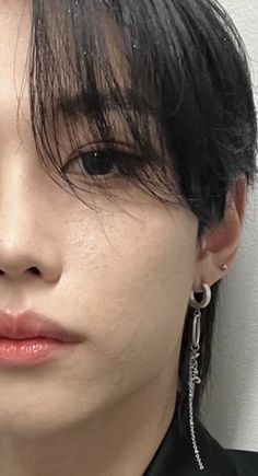 a close up of a person with black hair and piercings on their ears, wearing earrings