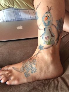 a person with a snowman tattoo on their foot next to an apple laptop computer