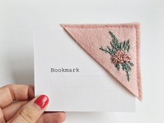 a hand holding a card with embroidered flowers on it