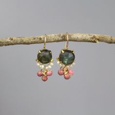 A pair of glowing and dainty clover earrings set with labradorite in copper bezel. Beautiful pearls encircle the lower part of the labradorite, and three striking rhodonite gemstones are interwoven gently. This unique labradorite earrings design is timeless, so you can enjoy it for years and years to come.  The hook is made of gold filled.  Materials:  Stone: labradorite, pearls, rhodonite Metal: gold filled, copper bezel Measurements:  Length including hook: 3cm Width: 15mm Labradorite in diameter: 10mm Since I mostly use natural gemstones, each jewel is unique and therefore there are subtle differences in color and form. Natural labradorite gemstone has lines and cleavage lines, and its fascinating color varies from grey and blue shades to green shades.  Pearl properties: Offers the powe Delicate Gemstone Drop Earrings, Dainty Dangle Earrings With Natural Stones, Dainty Natural Stone Dangle Earrings, Dainty Natural Stone Drop Earrings, Unique Jewelry Inspiration, Ocean Jewelry, Earrings Design, Clover Earrings, Labradorite Earrings