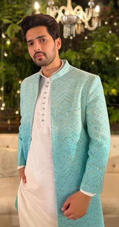 a man standing in front of a chandelier wearing a blue and white outfit