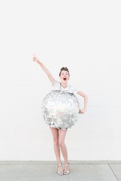 a woman wearing a sequin dress with her arms in the air